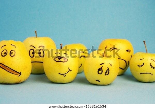 \
different emotions from joy to sadness and anger Face on an apple -\
abstract image of human emotions on blue\
background	