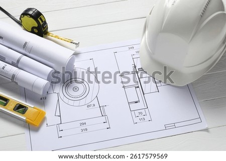 Different engineering drawings, hard hat, building level and measuring tape on white wooden table, above view