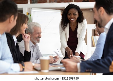 Different ethnicity and age businesspeople gathered together at boardroom for negotiations and planning future collaboration lead by african smiling businesswoman or corporate training process concept