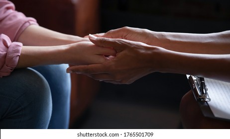 Different ethnicity female friends hold hands during confidential talk close up. Counsellor psychologist provide mental aid to patient at session in clinic, addicted patient professional help concept - Powered by Shutterstock