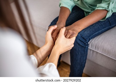 Different ethnicity female friends hold hands during confidential talk close up. Counsellor psychologist provide mental aid to patient at session in clinic, addicted patient professional help concept - Shutterstock ID 2027929202