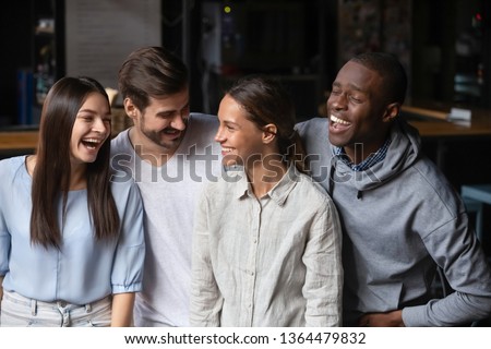 Different ethnicity millennial friends girls and guys standing in public place cafeteria laughing telling jokes people on the same wavelength having fun. Racial and ethnic equality, friendship concept