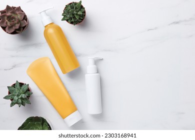 Different face cleansing products and potted succulents on white marble table, flat lay. Space for text - Shutterstock ID 2303168941