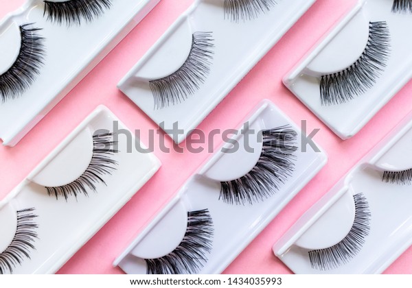 Different false eyelashes on\
a trendy pastel pink background. Beauty pop art pattern. Makeup\
accessories. Cosmetics products for women. Bright colorful\
backdrop. Close up.