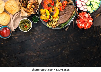 Different foods cooked on the grill, grilled steak and grilled vegetables on the wooden table with border. Top view. Outdoors Food Concept - Powered by Shutterstock