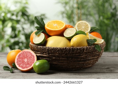 Different fresh citrus fruits and leaves in wicker basket on wooden table against blurred background, closeup - Powered by Shutterstock