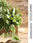 Different fresh herbs in basket on wooden table, closeup