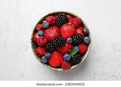 Different fresh ripe berries in bowl on light grey table, top view - Powered by Shutterstock