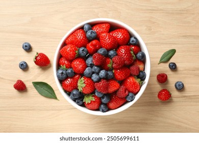 Different fresh ripe berries in bowl on wooden table, top view - Powered by Shutterstock