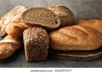 Different freshly baked bread loafs on grey table, closeup