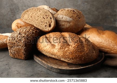 Different freshly baked bread loafs on grey table, closeup