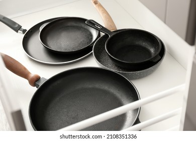 Different frying pans in open kitchen drawer, closeup