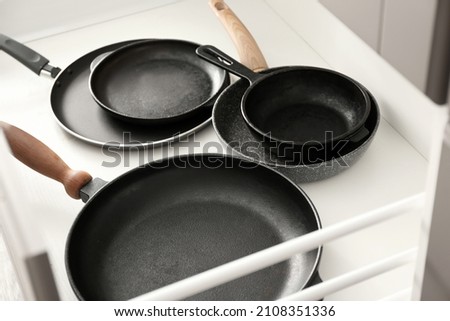 Different frying pans in open kitchen drawer, closeup