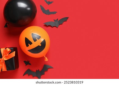 Different funny Halloween balloons with gift box and paper bats on red background - Powered by Shutterstock