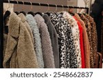 Different fur coats, winter outerwear hanging in a row on hangers in a fashion luxury boutique