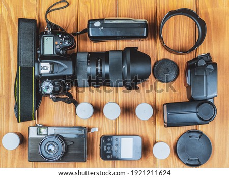 Different generations of cameras and flash with synchronizer on the background of wooden boards