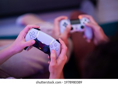 Different generations of PlayStation console controllers: PS5 DualSense controller and PS4 DualShock controller in a hands of gamers. Moscow - November 28 2020.