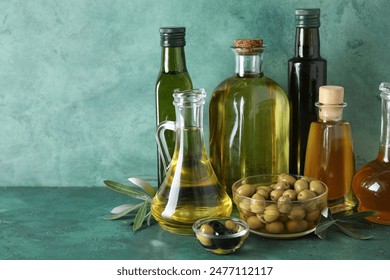 Different glassware of fresh olive oil on green background