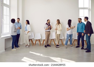 Different groups of colleagues communicate with each other during work break in coworking office. Multiracial stylish casual women and men work with each other in comfortable and positive atmosphere.