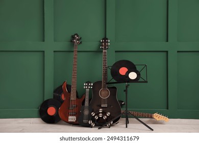 Different guitars, tambourine and vinyl disks near green wall - Powered by Shutterstock