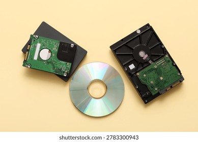 Different hard drives and CD disk on beige background