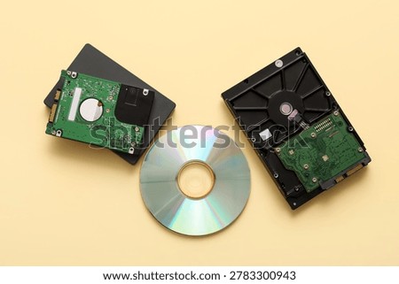 Different hard drives and CD disk on beige background