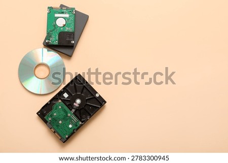 Different hard drives and CD disk on beige background