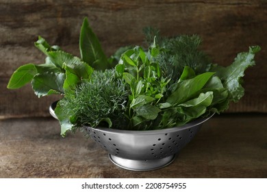 Different Herbs In Colander On Wooden Table