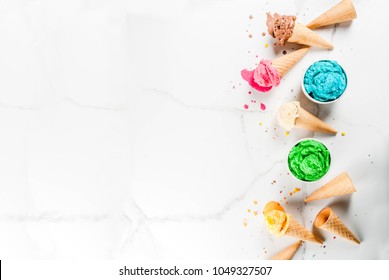 Different Homemade Melting Ice Cream In Bowls And Waffle Ice Cream Cones, White Vanilla, Orange, Pink Berry, Green, Blue, Chocolate White Marble Background  Copy Space Top View