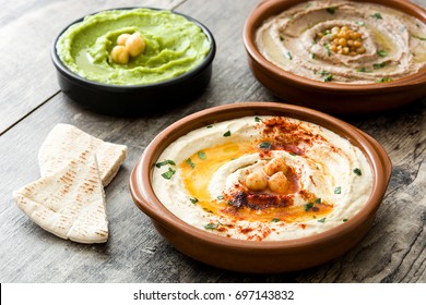 Different hummus bowls. Chickpea hummus, avocado hummus and lentils hummus on wooden table
 - Shutterstock ID 697143832