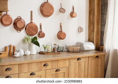 Different kind of cookware and ceramic plates on tabletop wooden kitchen. Set of copper saucepans, pans, pots and ladle hanging in kitchen. Hanging kitchen utensil on wall. kitchen interior decor
 - Shutterstock ID 2150980881