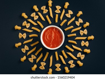 Different kind of pasta arrange on the table around pot with tomato sauce. Geometric pattern of pasta. Italian pasta with tomato sauce. - Powered by Shutterstock