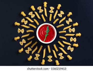 Different kind of pasta arrange on the table around pot with tomato sauce. Geometric pattern of pasta. Italian pasta with tomato sauce. - Powered by Shutterstock