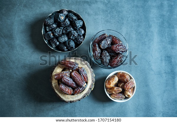 Different kind of raw date fruit ready to eat on\
concrete background. Traditional, delicious and healthy ramadan\
food. Medina, Iranian, Baghdad and Medjoul dates specific to their\
region. Top view \
