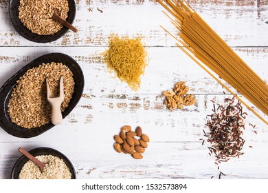 Different Kind Of Whole Grains In Bowls And Spread In A White Table
