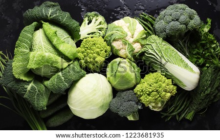 Different kinds of cabbage background in black table. Green vegetables. Broccoli, Savoy cabbage, White cabbage, cauliflower, Peking cabbage. Cucumbers, asparagus, herbs. Healthy diet food.