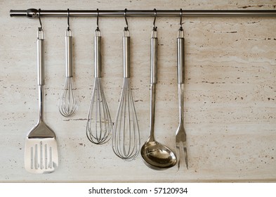 Different Kitchen Tools For Cooking (kitchenware) Hanging On The Wall