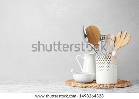Different kitchen utensils on table against light background. Space for text