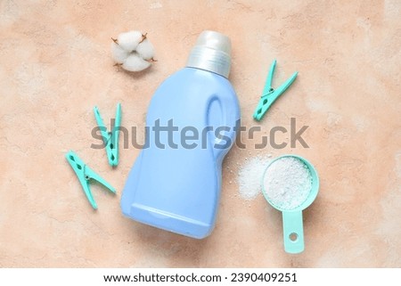 Different laundry detergents with cotton flower and clothespins on beige grunge background