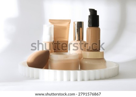 Different liquid foundations, face powder and makeup sponge on white background, closeup