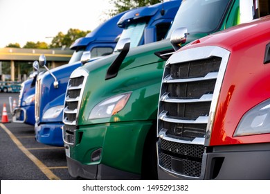 Different Make And Models Big Rigs Semi Trucks With Semi Trailers Standing In Row On Truck Stop Parking Lot For Rest And Comply With The Movement According To The Schedule For Successful Delivery