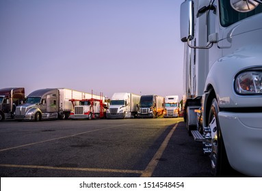 Different Make And Models Big Rigs Semi Trucks With Semi Trailers Standing In Row On Truck Stop Parking Lot For Rest And Comply With The Movement According To The Schedule For Successful Delivery