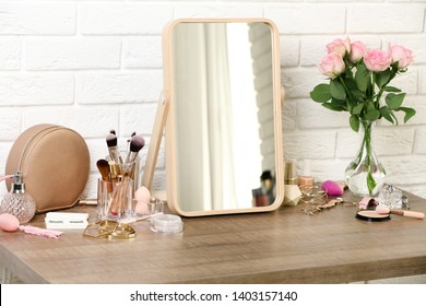Different makeup products and accessories on dressing table in room interior