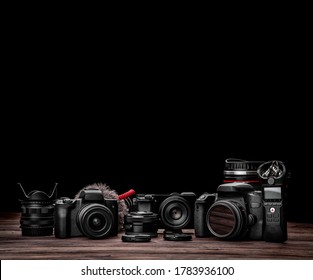 Different modern cameras and lenses on a wooden table. Technique for shooting photos and videos. Video blogger kit. Postcard concept for photographer and videographer.