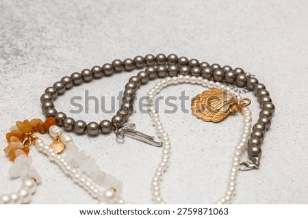 Different necklaces made from beads, shells, and pearls are arranged on a light gray surface for an organized view. Each piece shows unique features and designs.