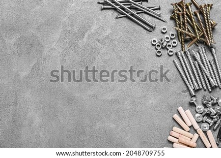 Different nuts, bolts, screws, nails and dowels on grey background