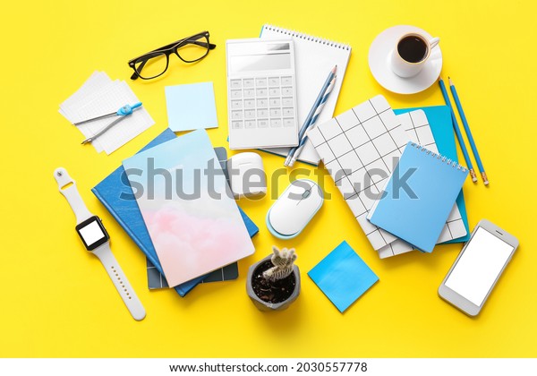 Different office tools, cup of coffee, glasses and
devices on color
table