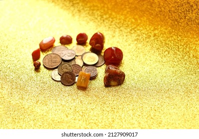 different old coins, stone rune Fehu and minerals on  yellow shiny glittering blurred background close up.  Magic for attracting money, wealth. witchcraft money esoteric ritual. selective focus