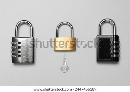 Different padlocks and key on grey background, flat lay