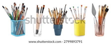 Different paint brushes in holders isolated on white, set